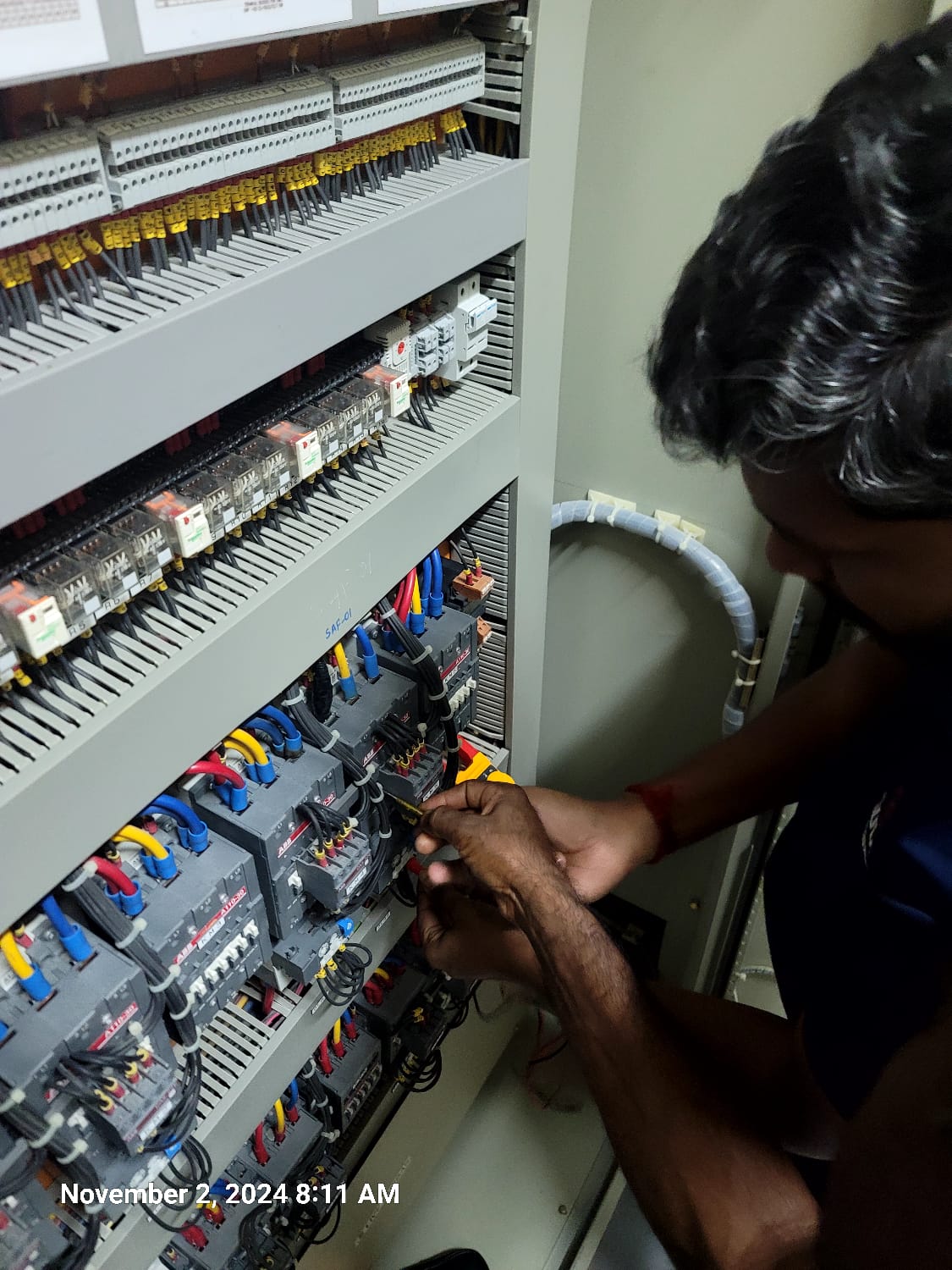Servicing relays and contactors inside a control panel during maintenance.